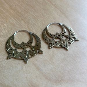 Gold colored metal hoop earrings in Aztec tribal design